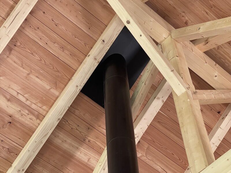 Schornstein am Deckendurchgang zwischen sichtbaren Holzbalken