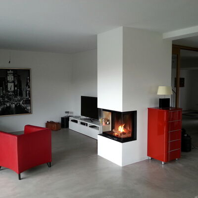 Moderner Panoramakamin als Raumteiler mit mehrseitiger Feuersicht und schwarzem Feuertisch im offenen Wohnraum.